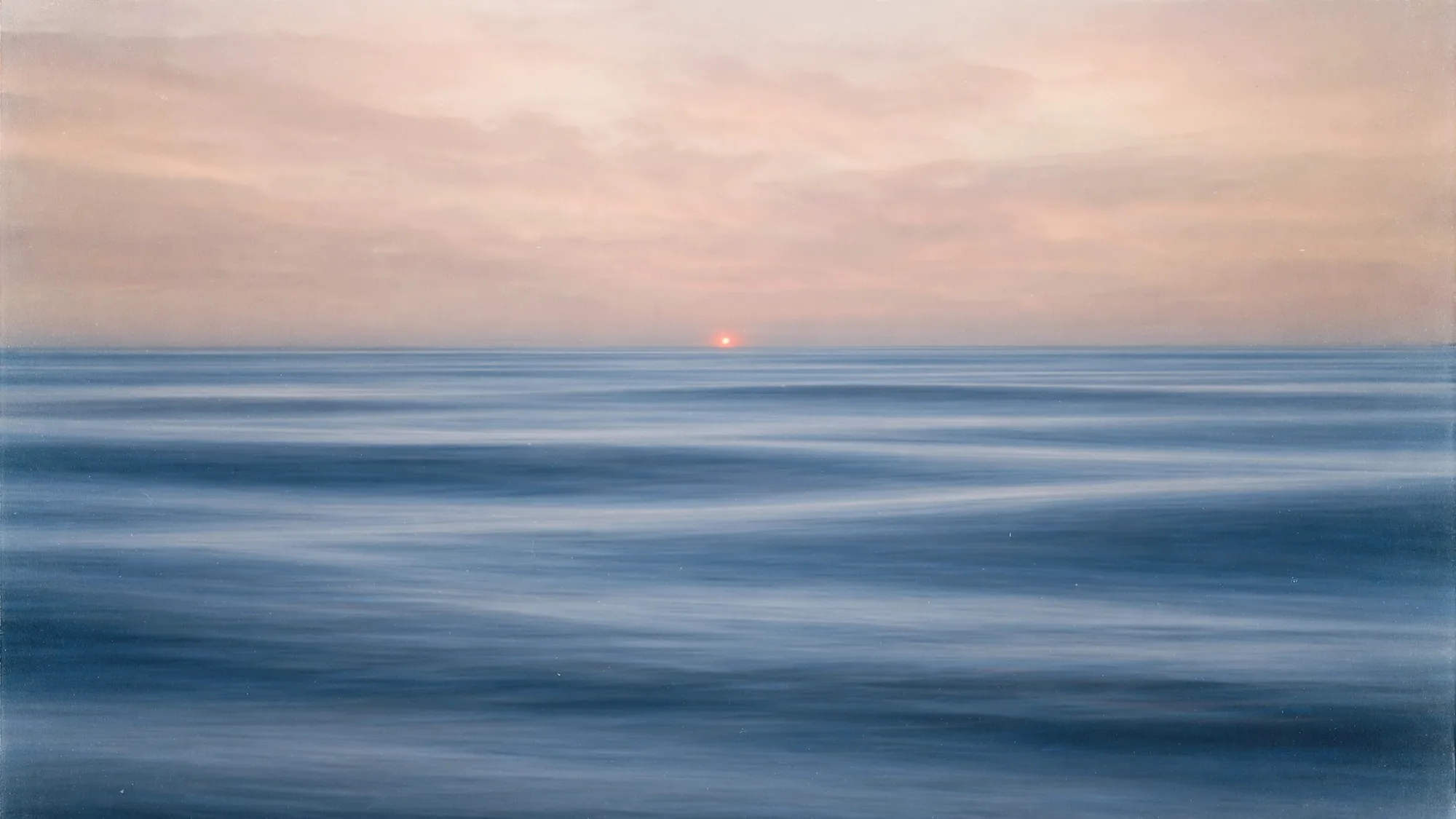 The sea at dusk, ships passing far away, Nano watching from a rock.